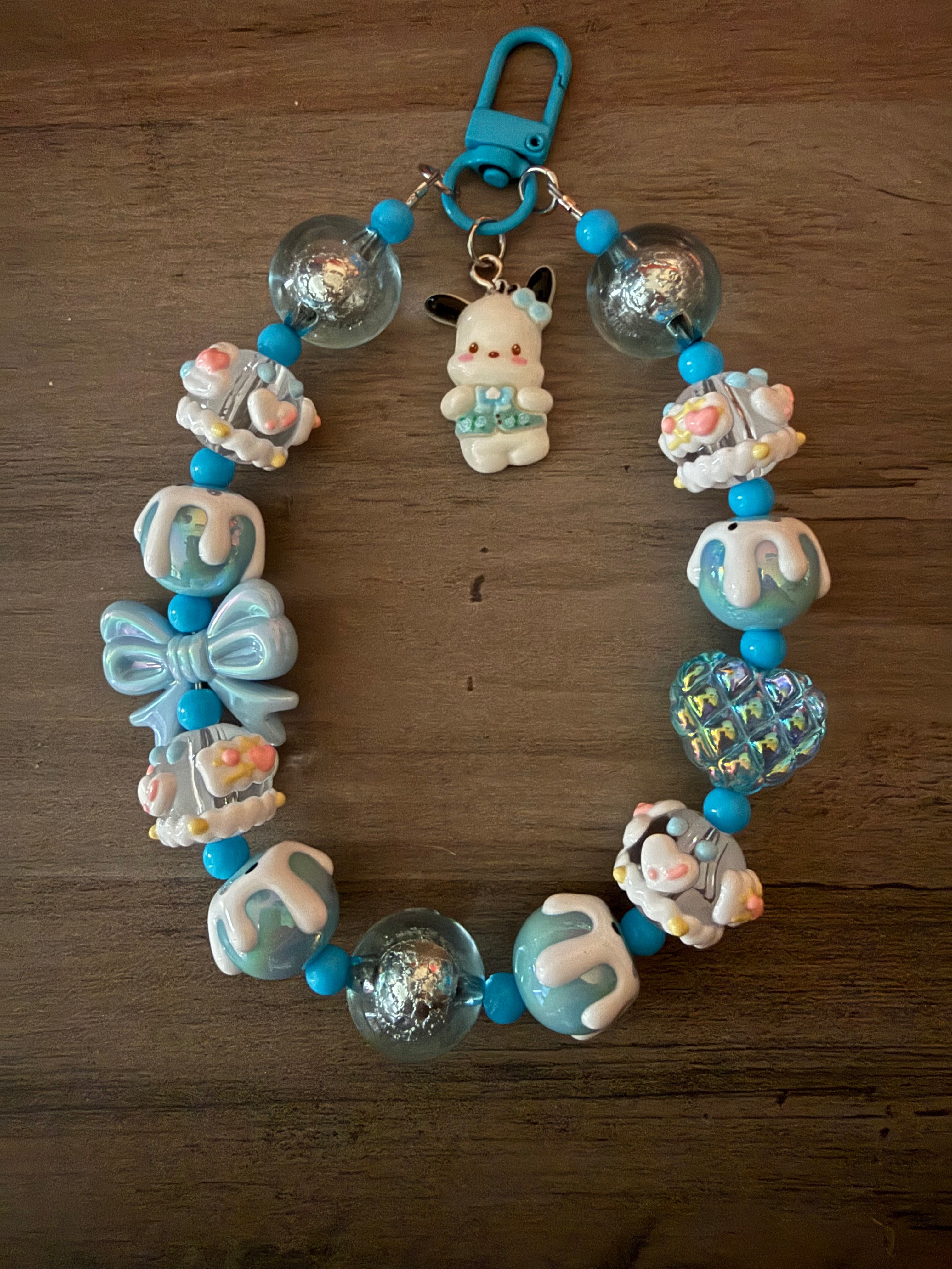 Colorful beaded keychain featuring a cute pochacco inspired charm, blue and white decorative beads, a bow, and various playful elements.