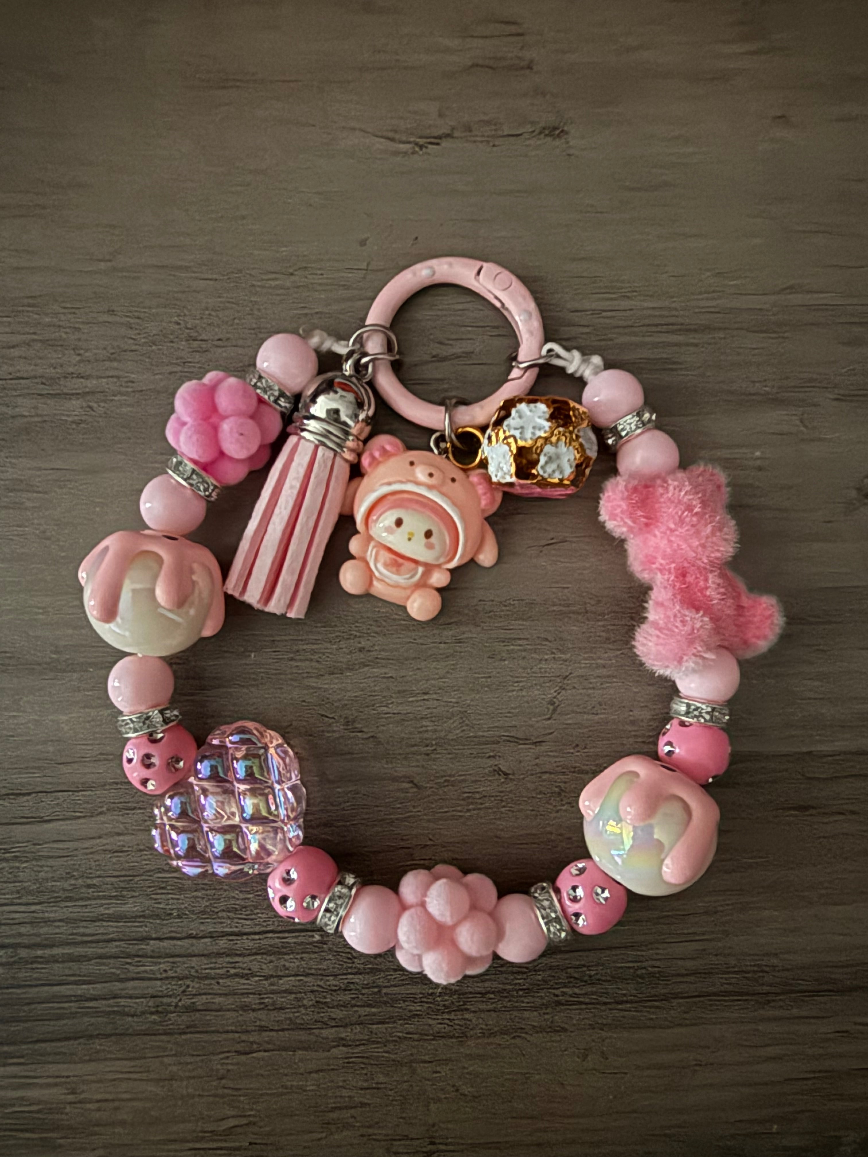 A pink beaded silicone wristlet keychain featuring a My Melody charm, a fuzzy bear, a tassel, and various decorative textured beads.