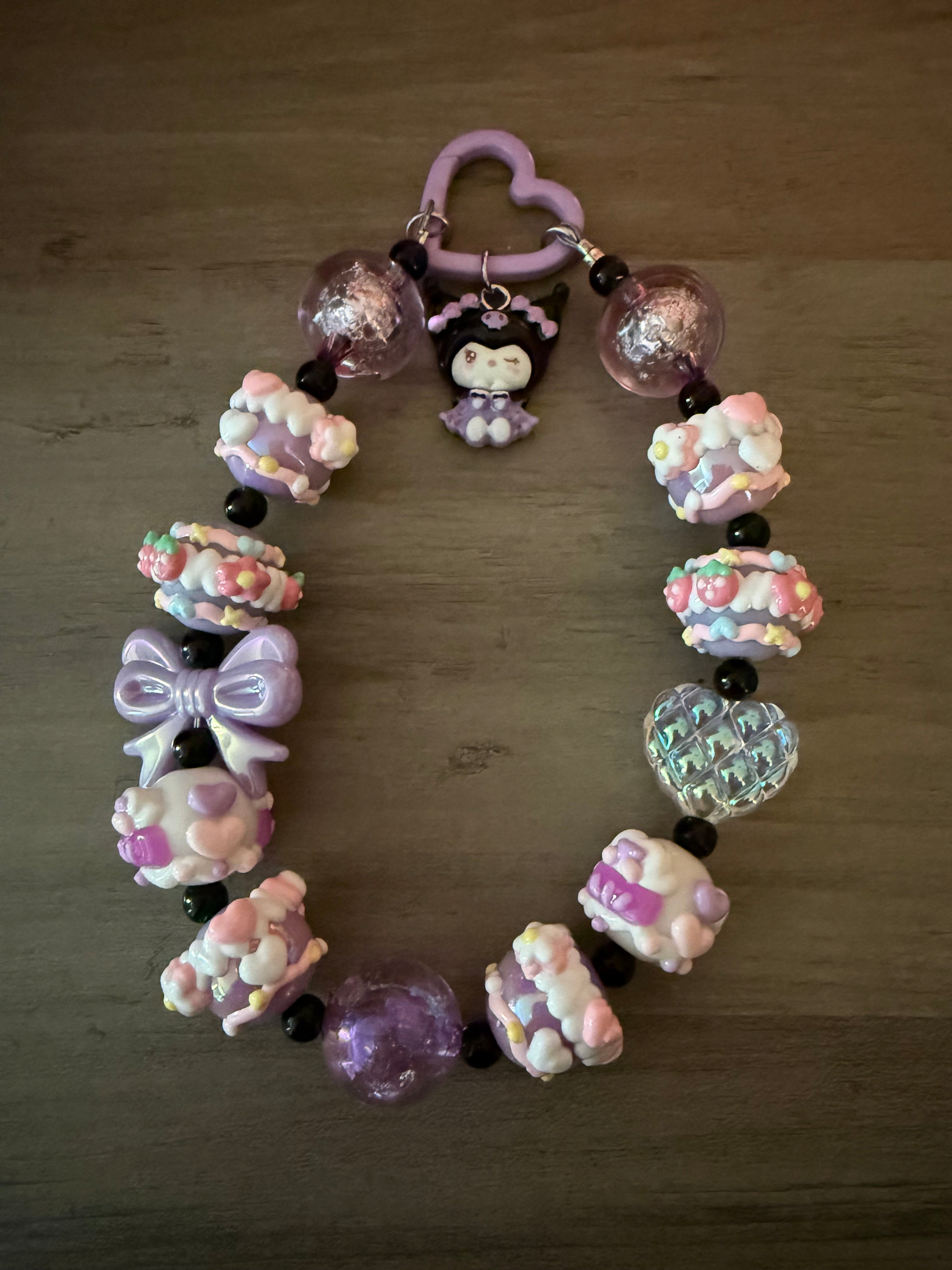 Colorful beaded keychain featuring a cute kuromi inspired charm, purple and pink beads, a bow, and various decorative elements.