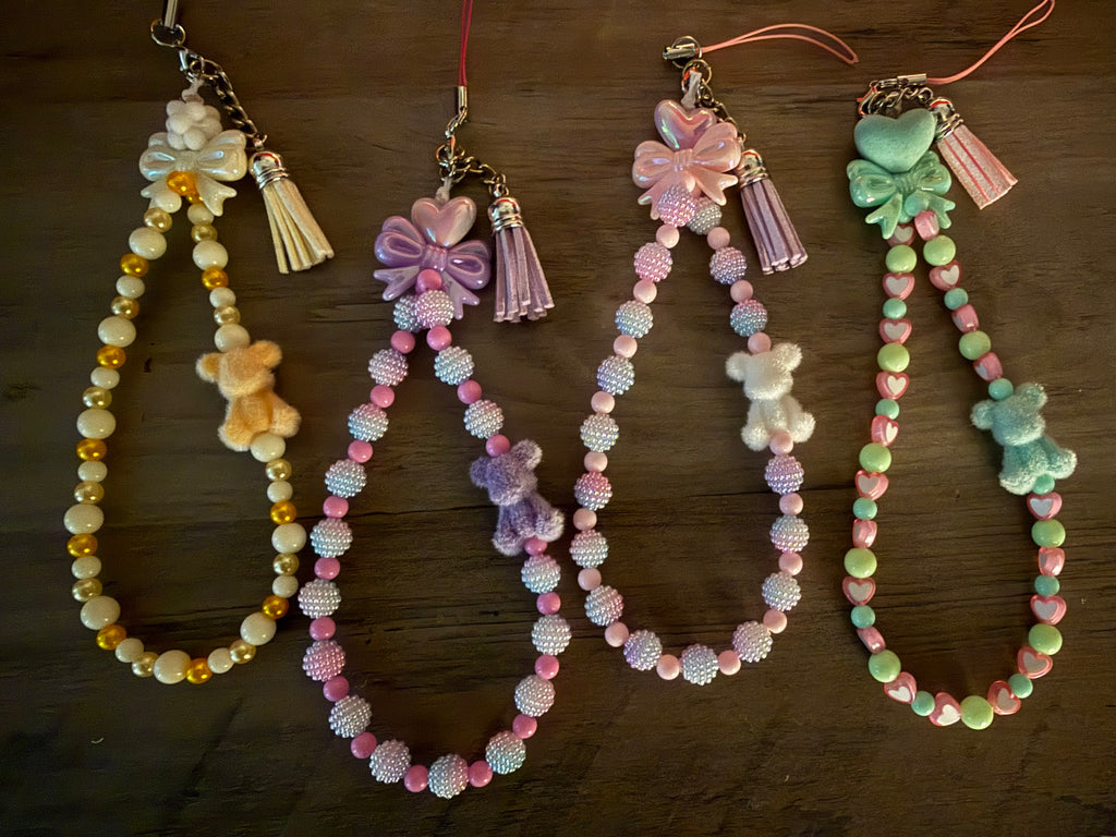 Four handmade beaded phone charms with bows, tassels, and miniature bear figures.
