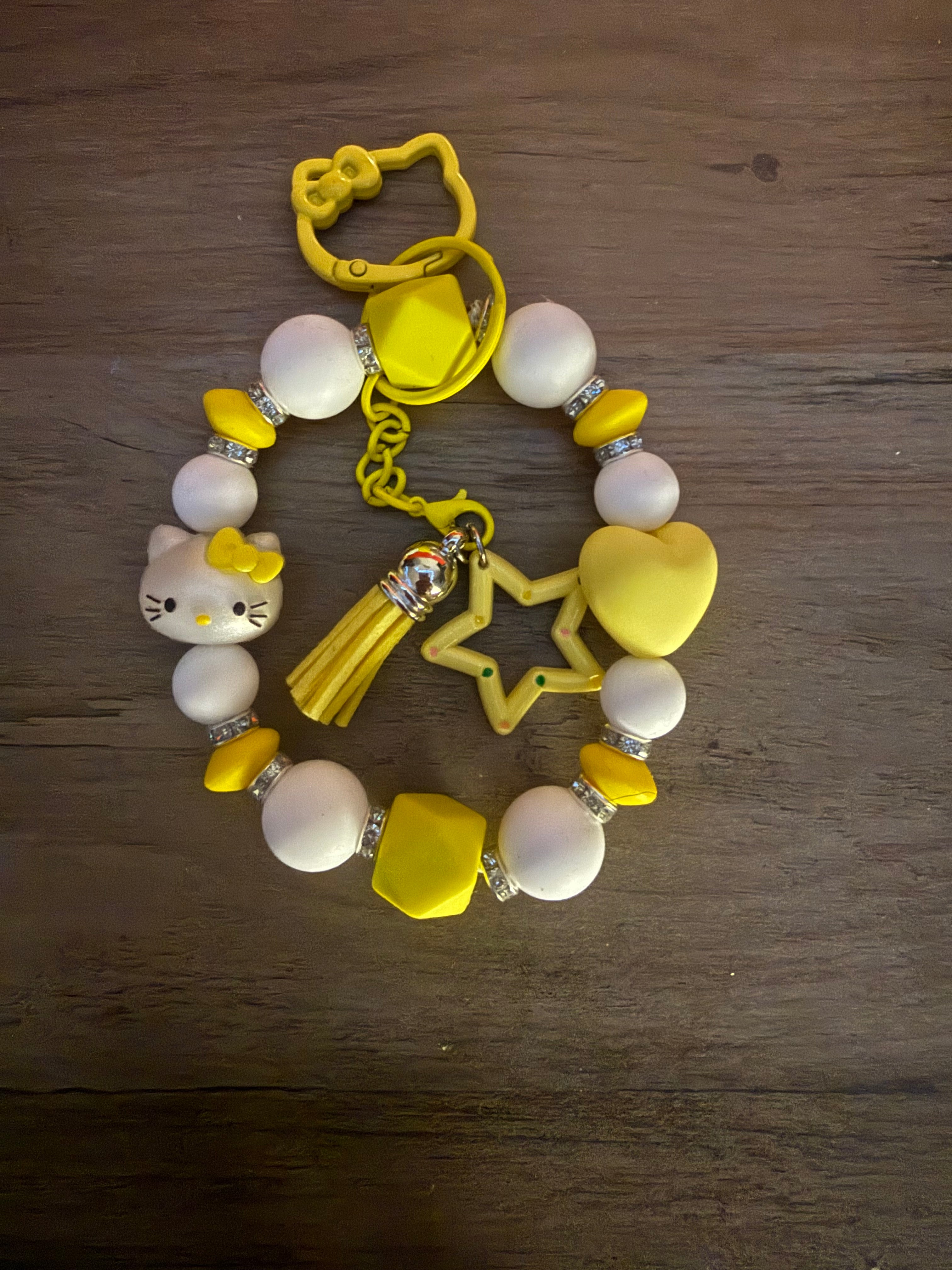Colorful beaded keychain featuring a Hello Kitty charm, yellow and white beads, a star pendant, a heart charm, and a tassel.