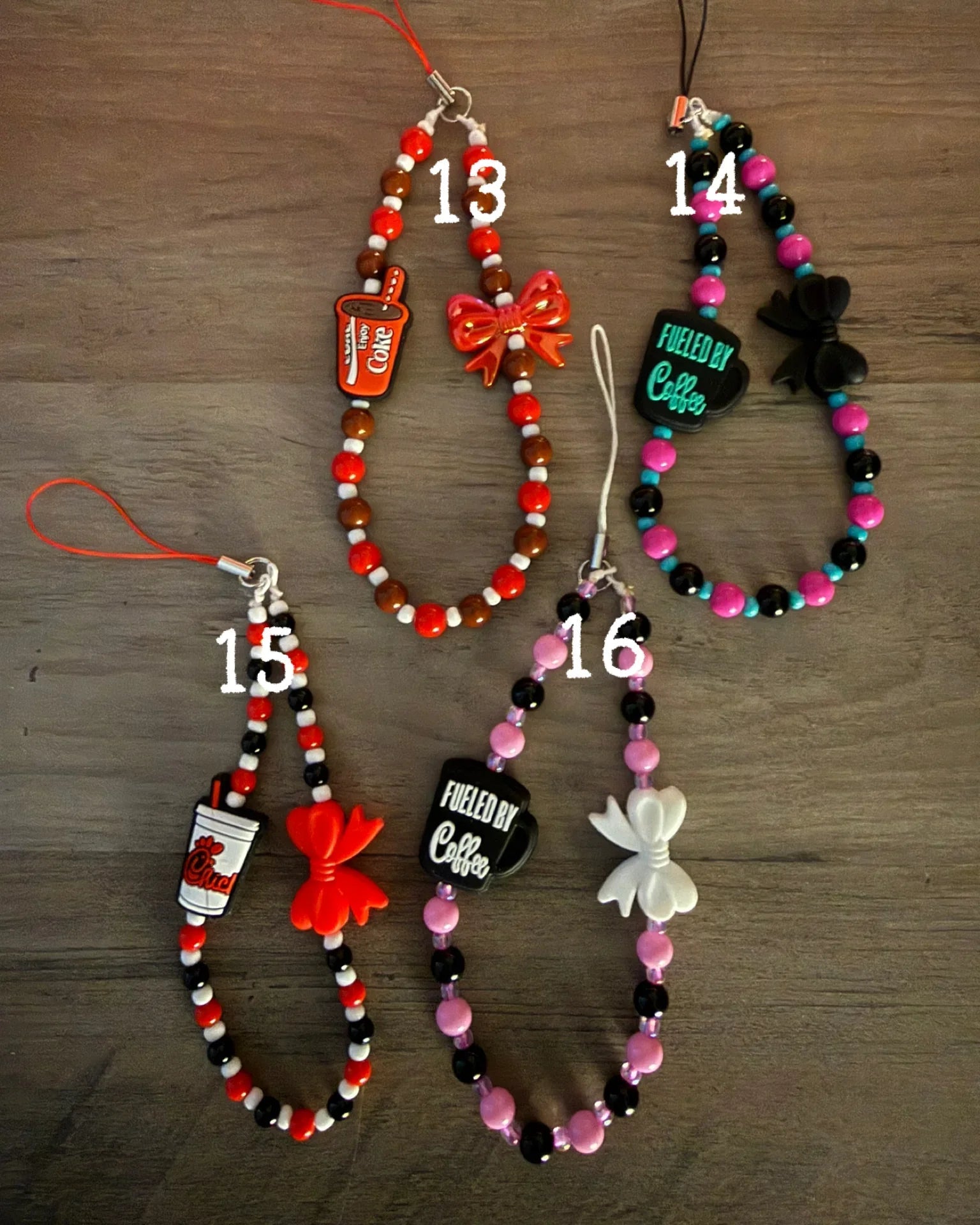 A collection of colorful phone charms, soda cups, coffee cups, and bows, with vibrant beads in red, black, pink, and brown.