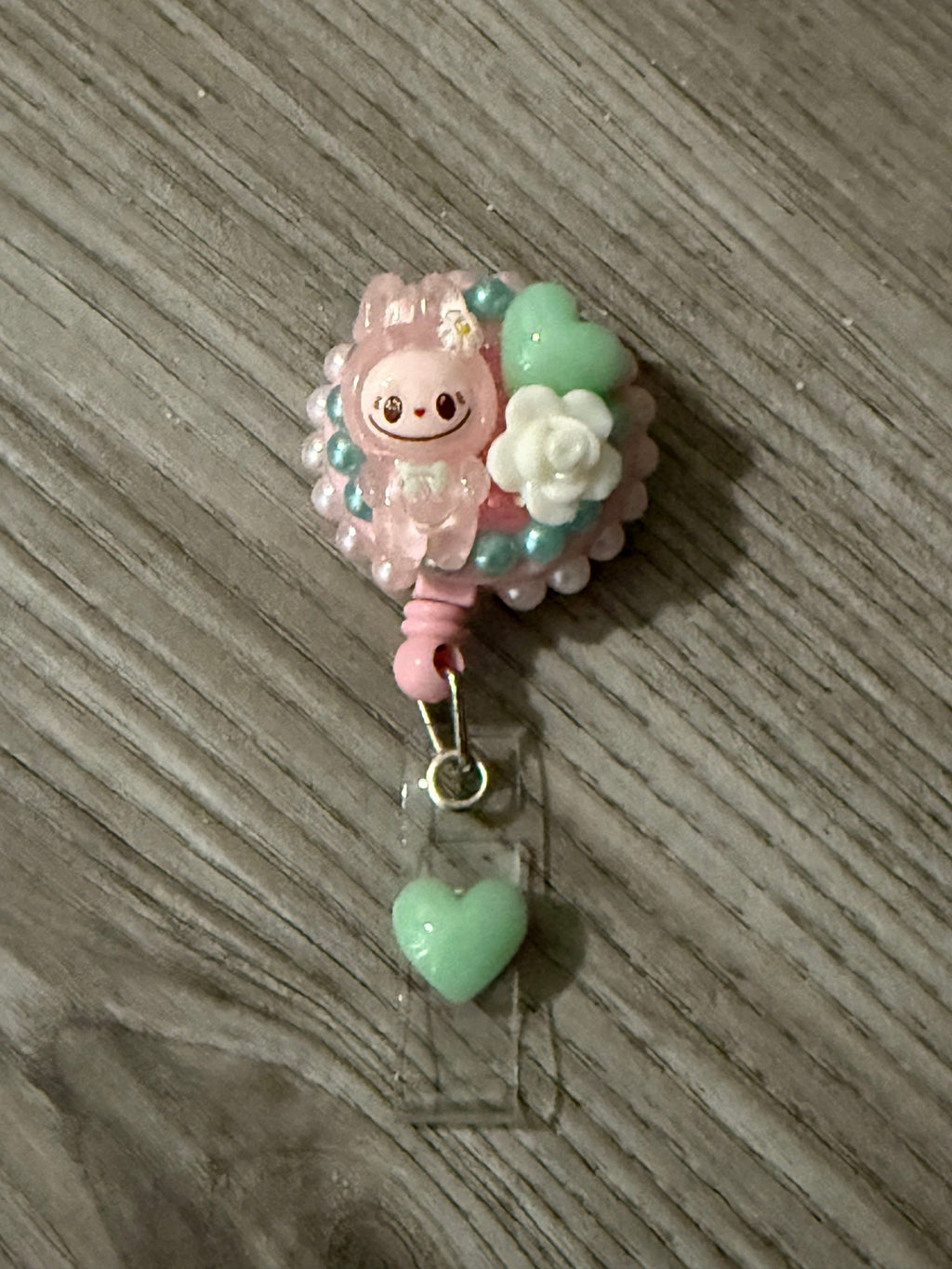 Handmade pink decoden badge reel featuring a Labubu character, mint green hearts, and a white rose charm.