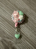 Handmade pink decoden badge reel featuring a Labubu character, mint green hearts, and a white rose charm.