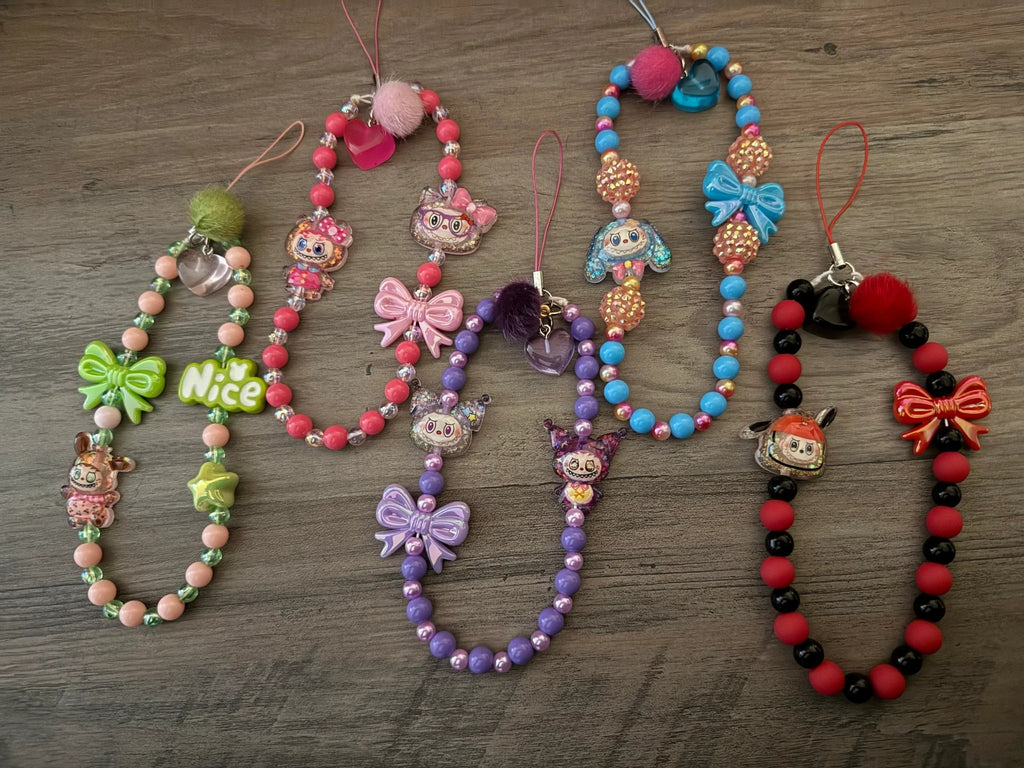Colorful collection of handmade phone charms featuring playful designs, including cute characters, bows, and vibrant beads.