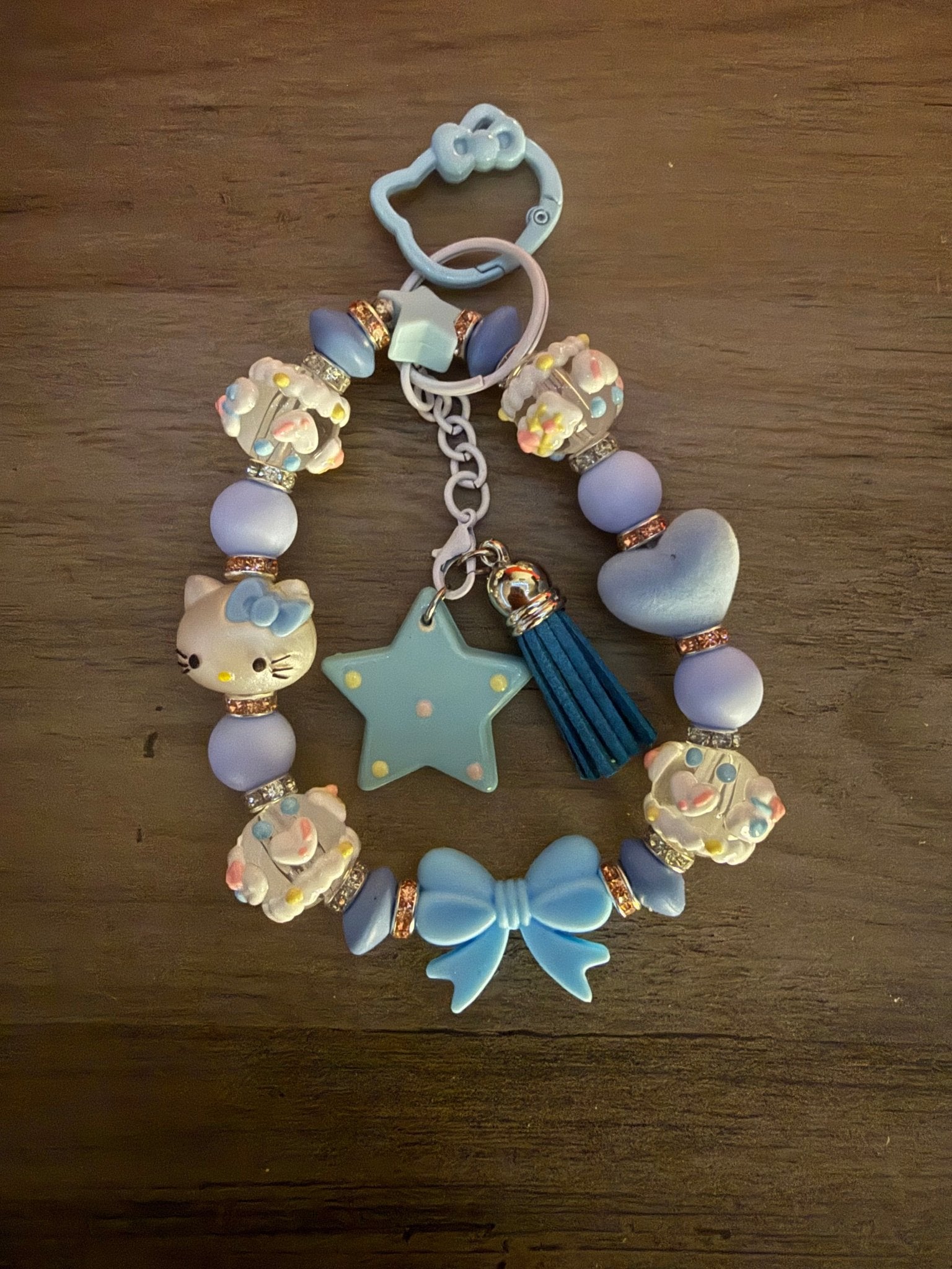 Handmade blue and lavender Hello Kitty beaded wristlet with a tassel, star charm, and blue character-shaped clasp.