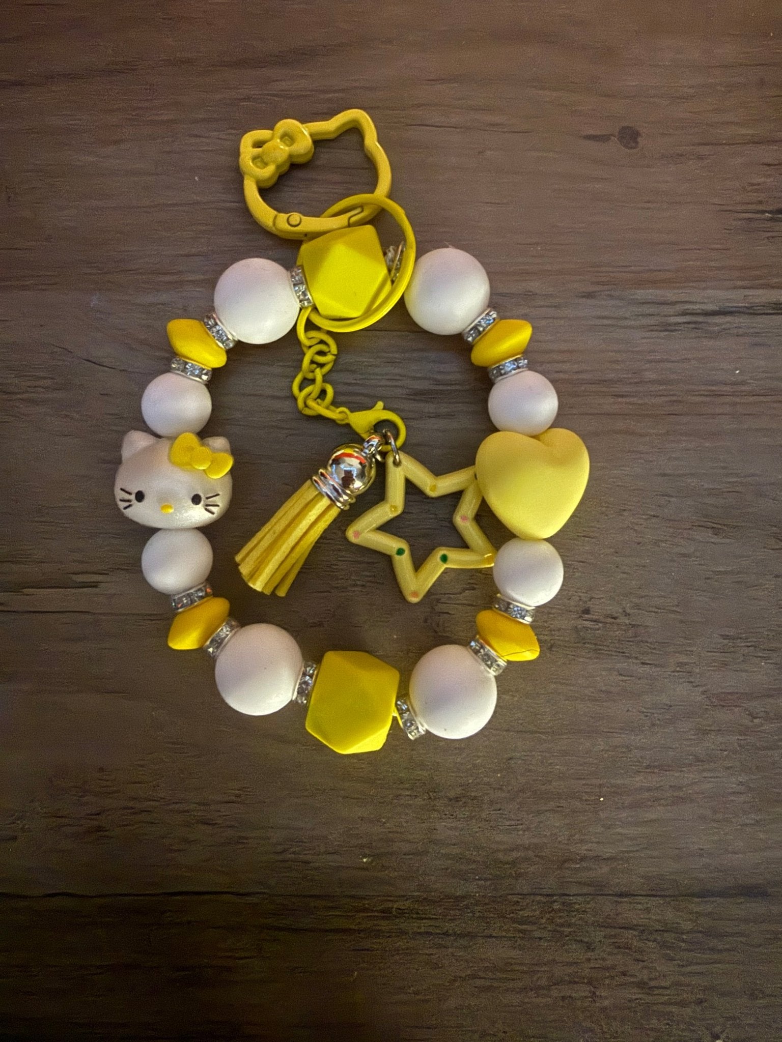 Handmade yellow and white Hello Kitty beaded wristlet with a tassel, star charm, and yellow character-shaped clasp.