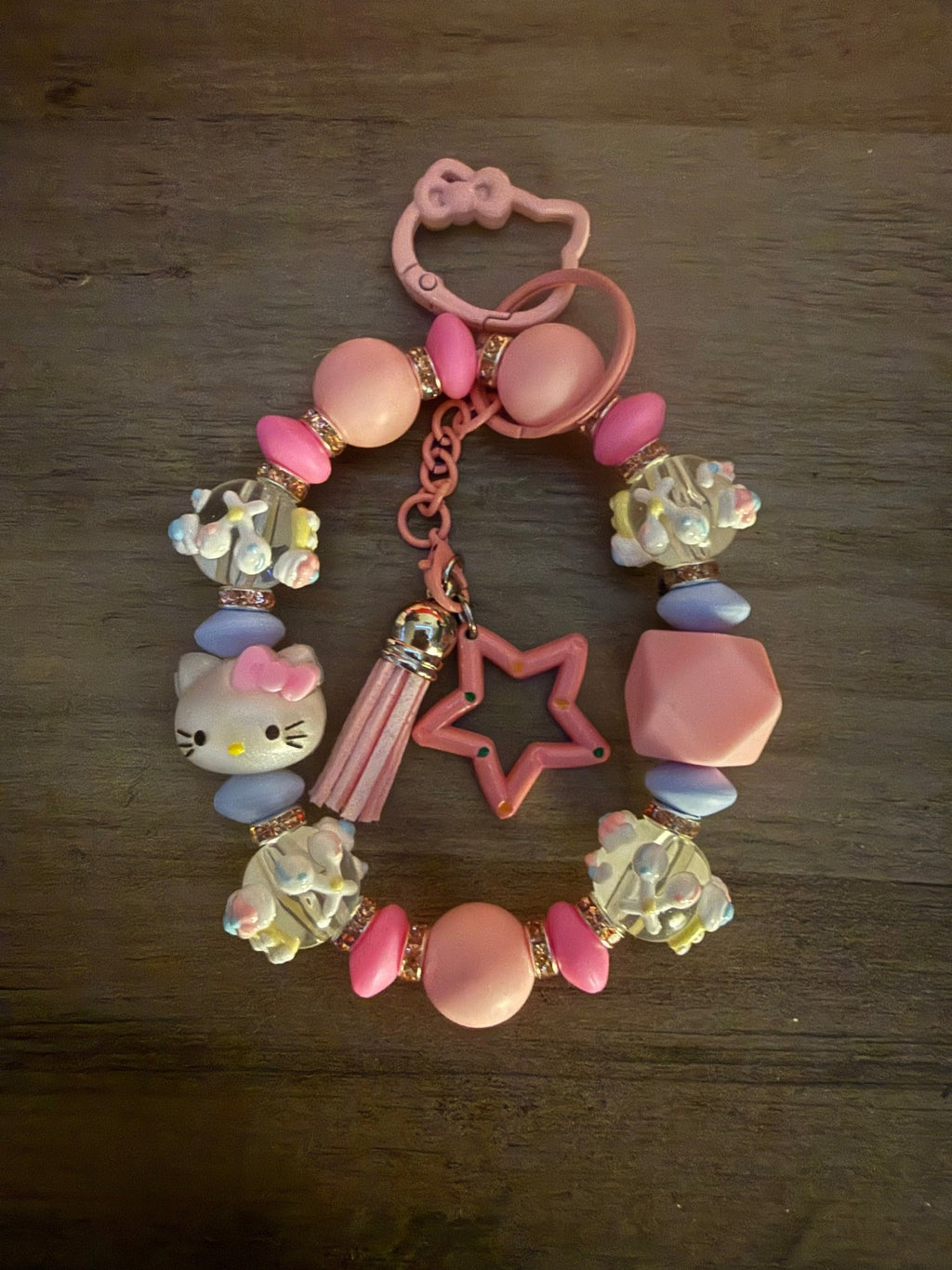 Handmade pink and lavender Hello Kitty beaded wristlet with a tassel, star charm, and character-shaped clasp.