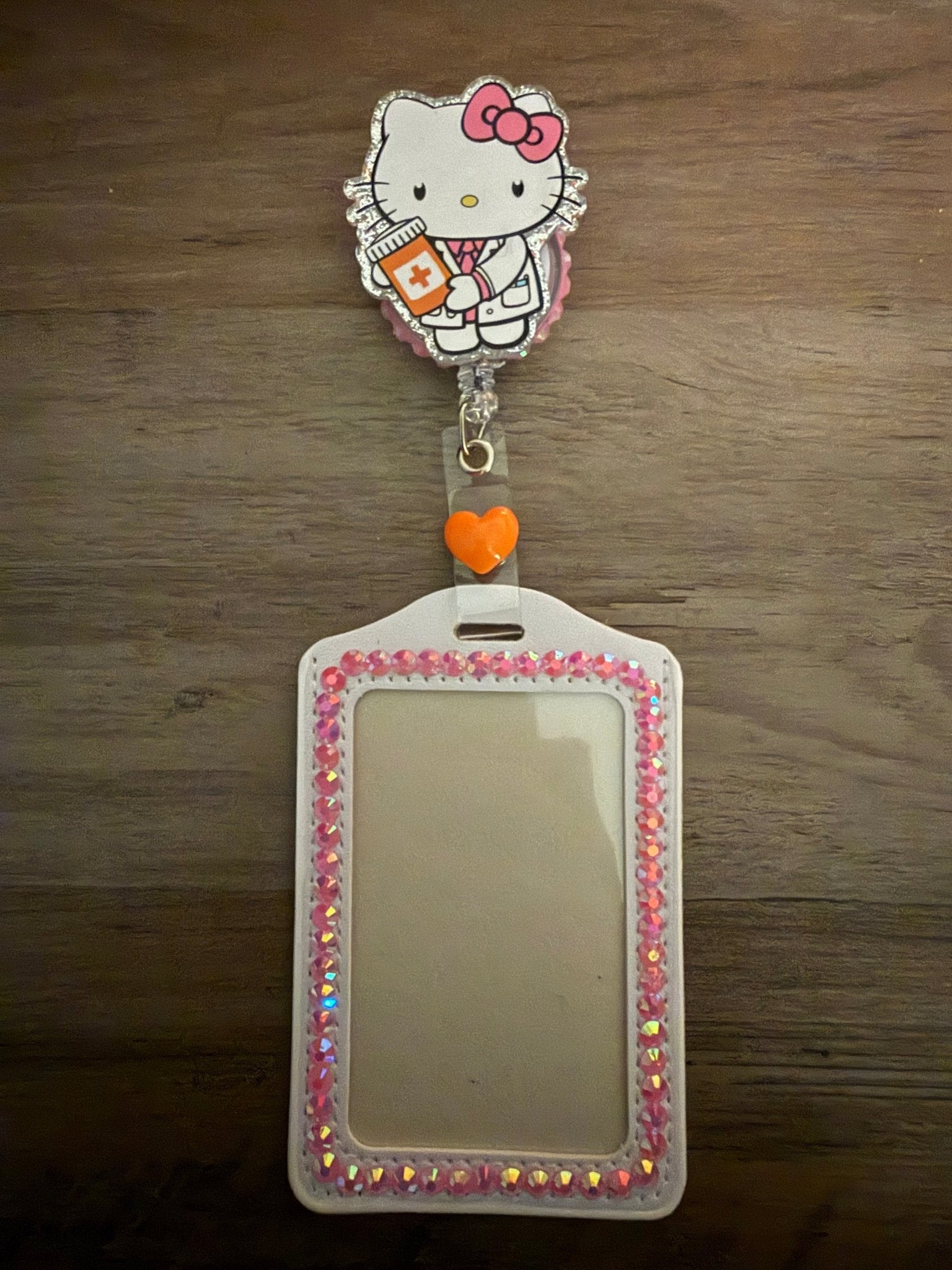 Handmade Hello Kitty nurse badge reel and white ID holder lined with pink iridescent rhinestones and an orange heart.