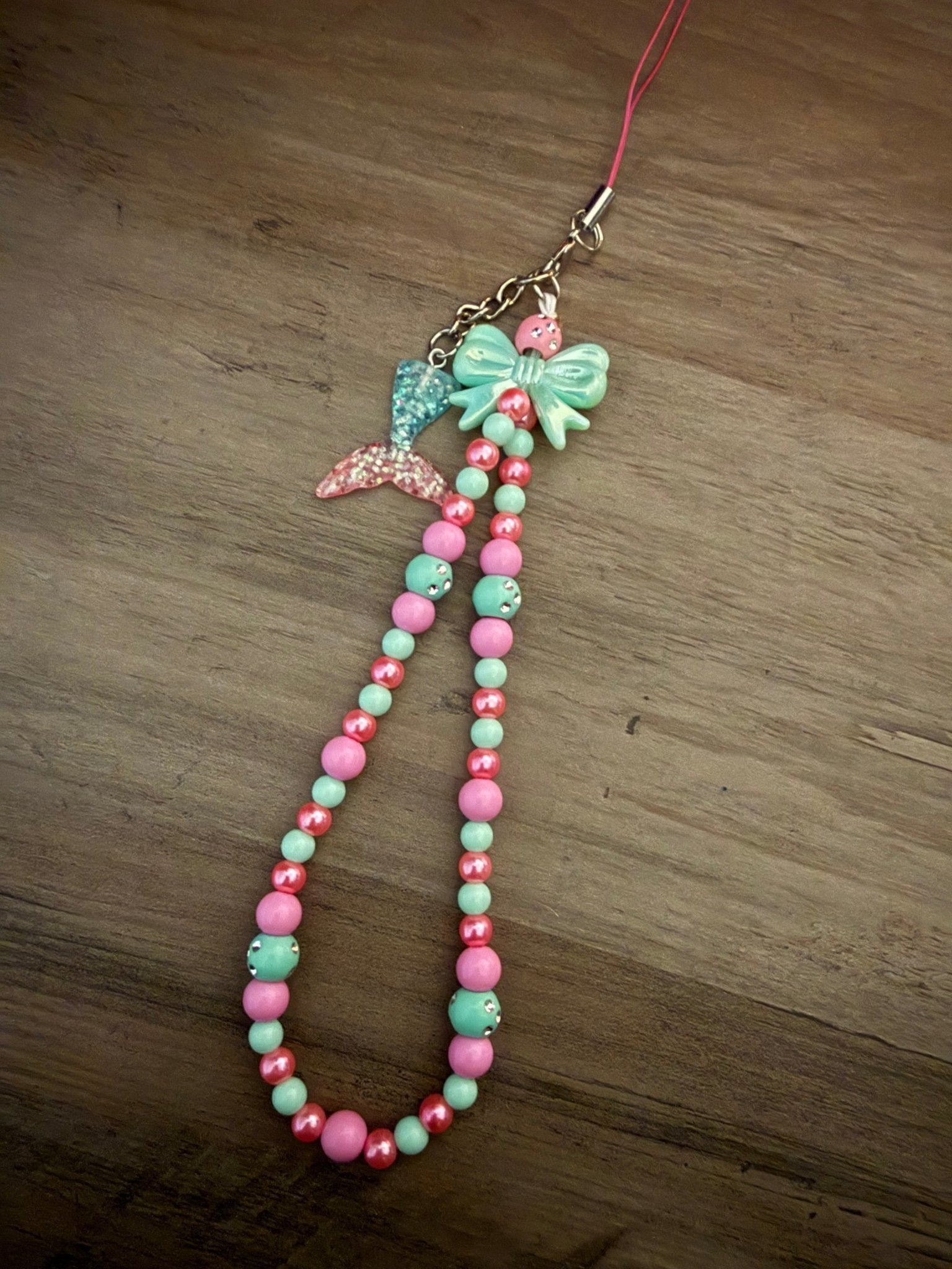 Handmade pink and mint beaded phone wristlet with a mermaid tail charm and a mint bow.