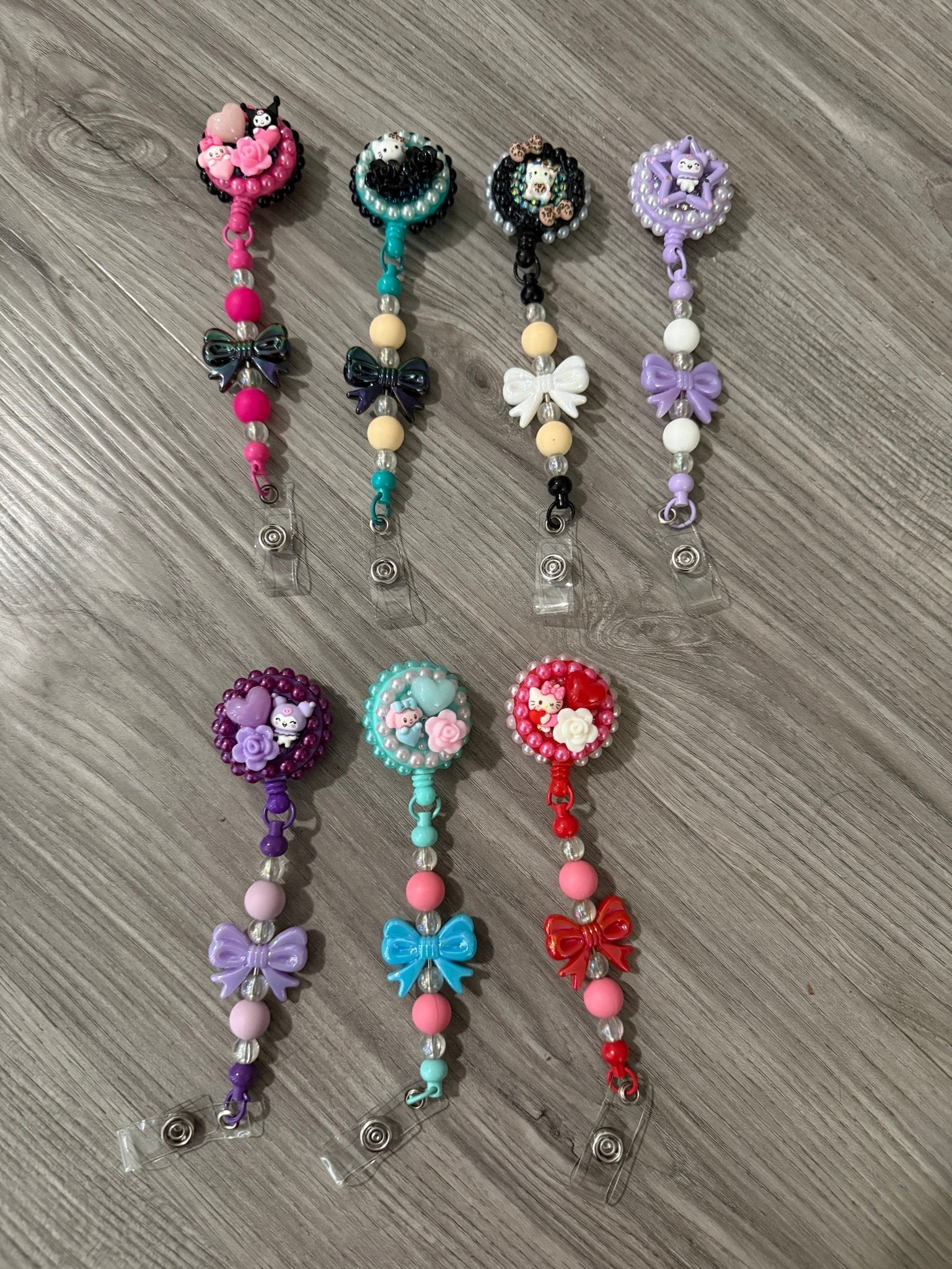 A collection of colorful badge reels featuring playful designs, including bows, flowers, and cute characters.