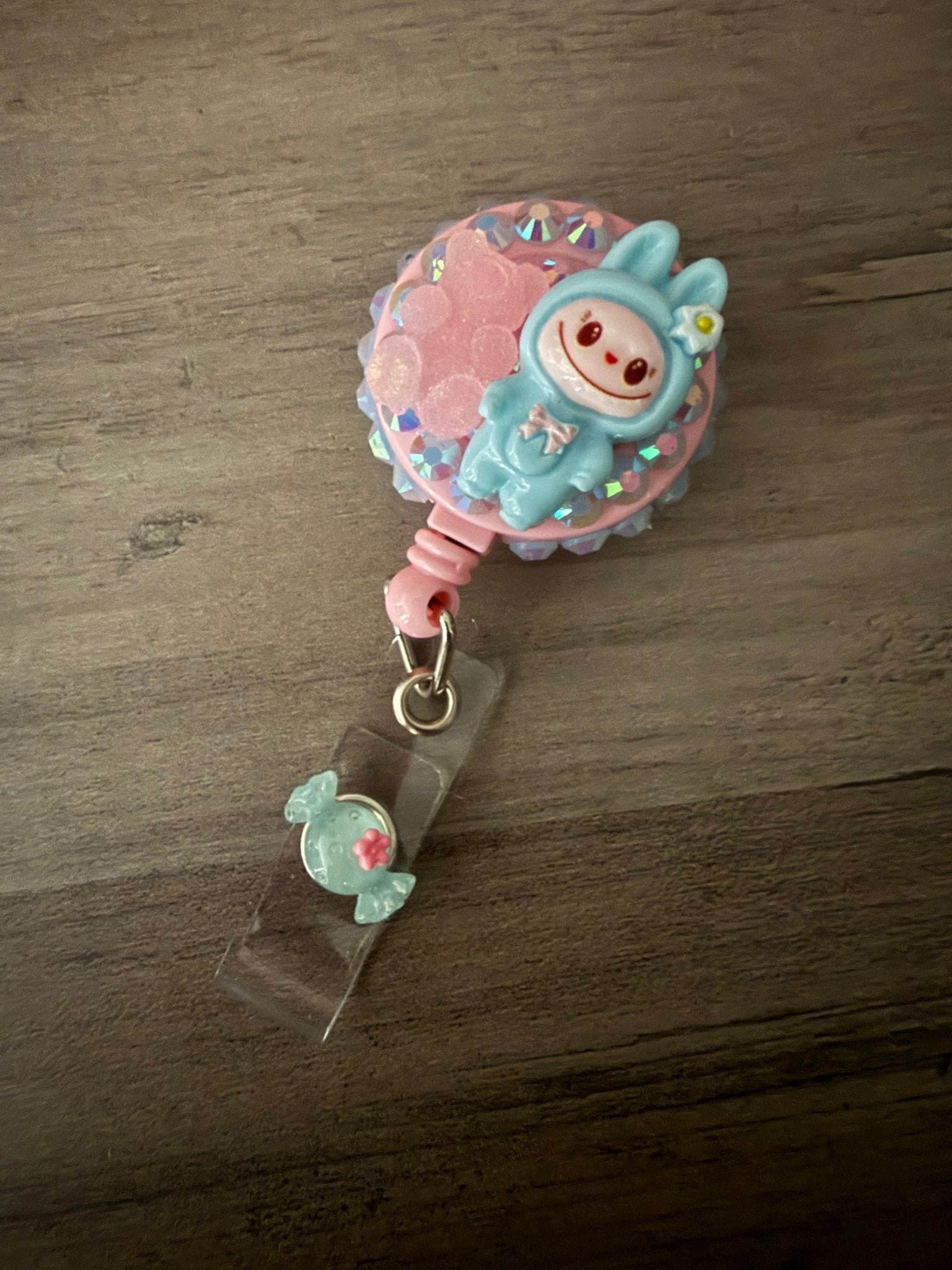 Handmade blue monster badge reel embellished with iridescent rhinestones, a pink gummy bear, and a mint candy charm.
