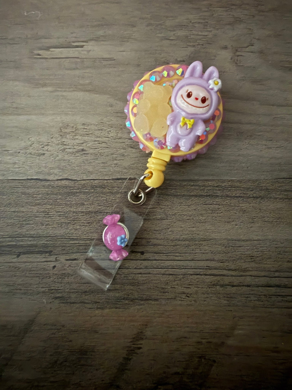 Handmade purple monster badge reel embellished with pink rhinestones, a yellow gummy bear, and a purple candy charm.