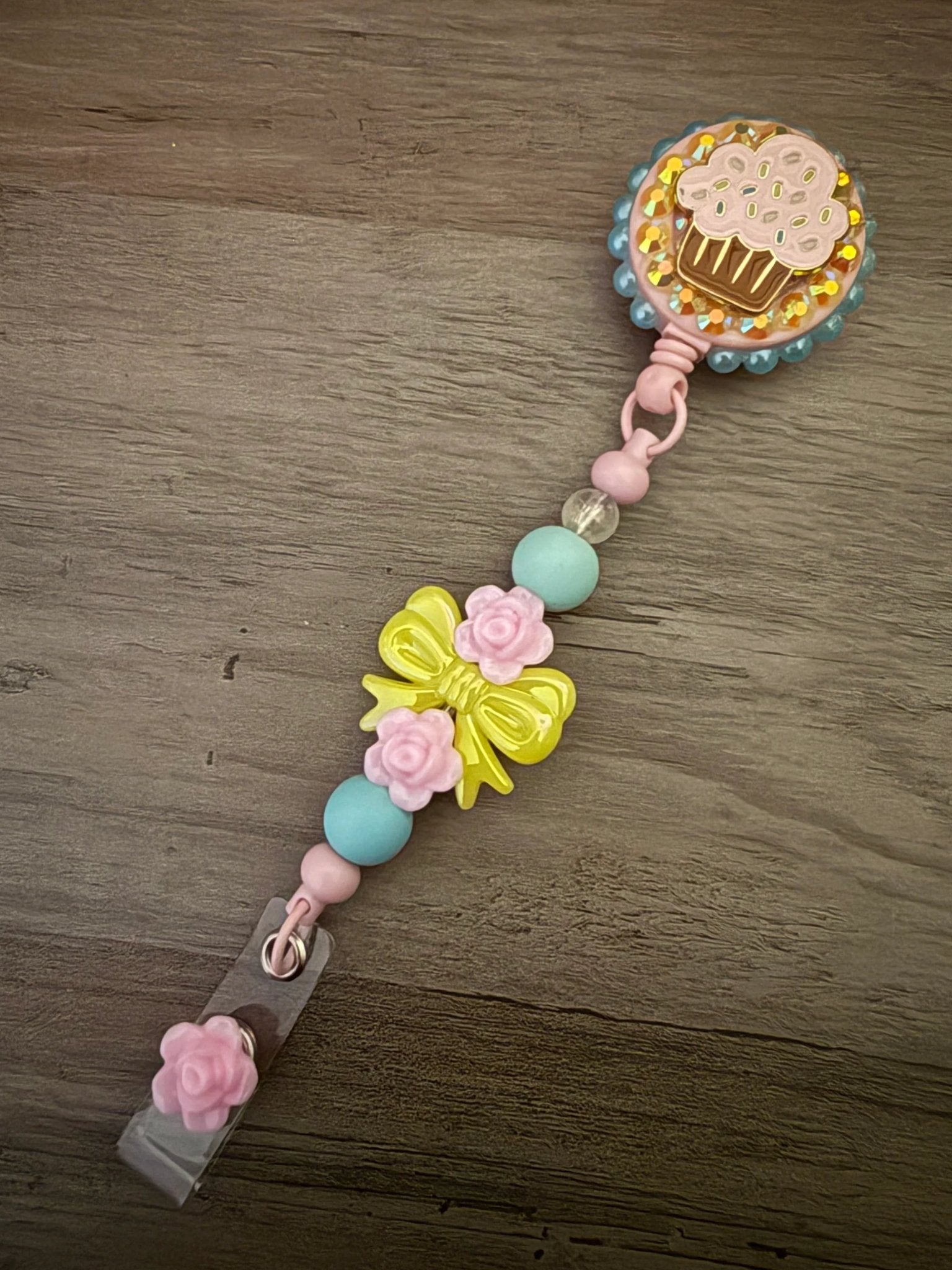 Colorful badge reel featuring a cupcake design, adorned with pink and yellow beads, and flower accents.