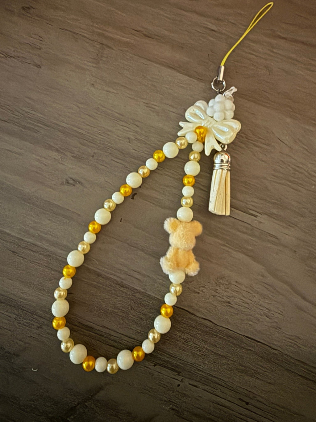 Handmade cream and gold beaded phone wristlet with a fuzzy teddy bear charm, white bow, and matching tassel.